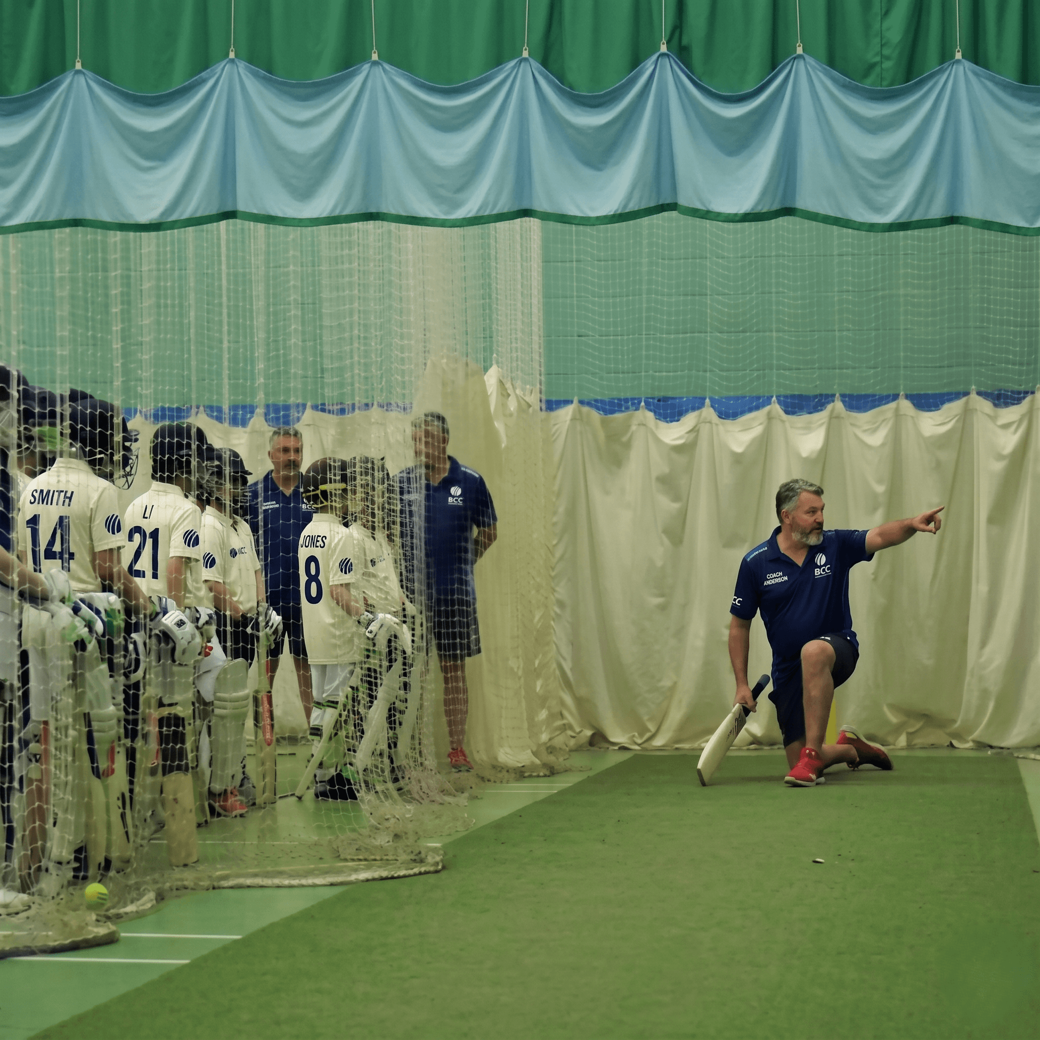 BCC coach providing one-on-one bowling technique advice to a player